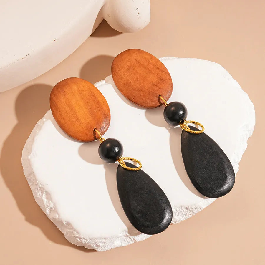 Brown and black wooden elliptical earrings with silver needle details on retro background