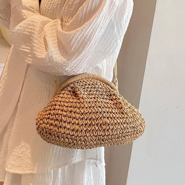 Women's khaki straw shoulder bag with chain detail and shell shape on a neutral background