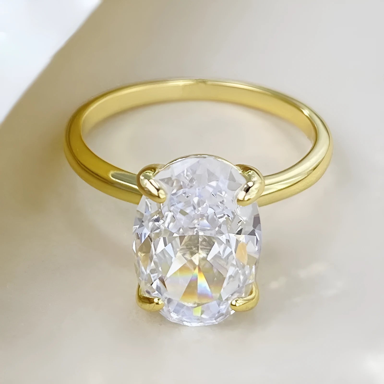 Women's oval 9K silver ring with a four-prong setting, shown in gold and silver tone finishes.