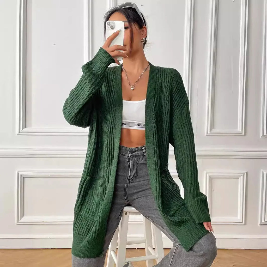 A women's loose dark green cardigan sweater with two pockets and long sleeves.