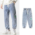 Men's loose-fit tapered cotton trousers in black, blue, or grey on a mid-waist.