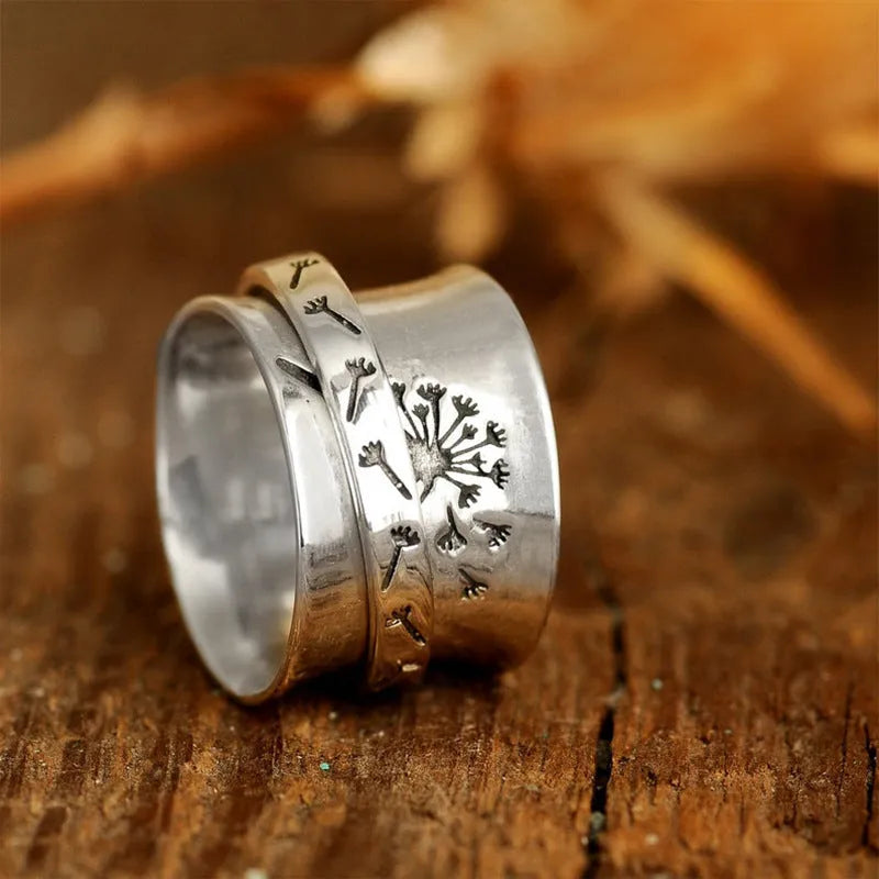 Silver coloured rotating flower fashion ring on a hand, showing adjustable band and floral design.