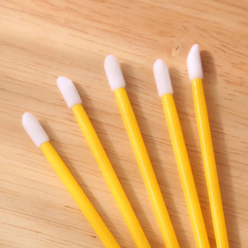 Pack of disposable flocked lip brush applicators with coloured handles on a white surface.