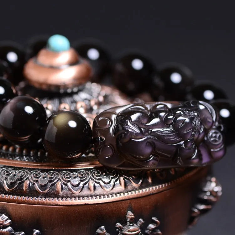Polished natural crystal Pi Xiu bracelet with geometric ethnic design on a wrist.