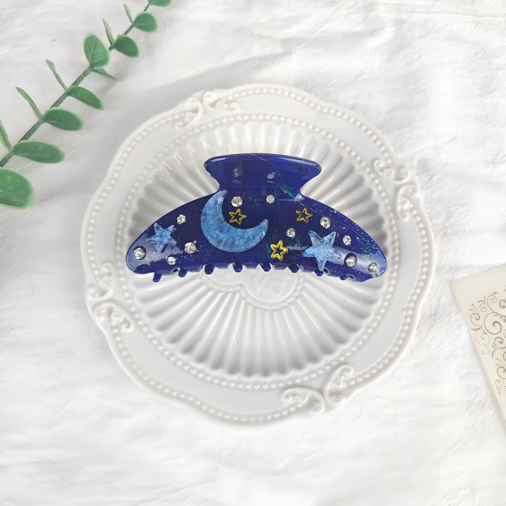 Oversized women's barrette with blue star moon starry sky pattern on a cellulose acetate clip.
