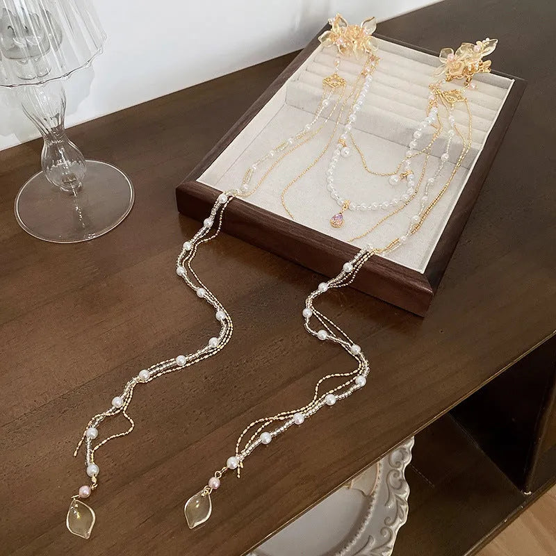 Gold coloured women's hairpin with a pearl, diamond flower and long decorative tassels.