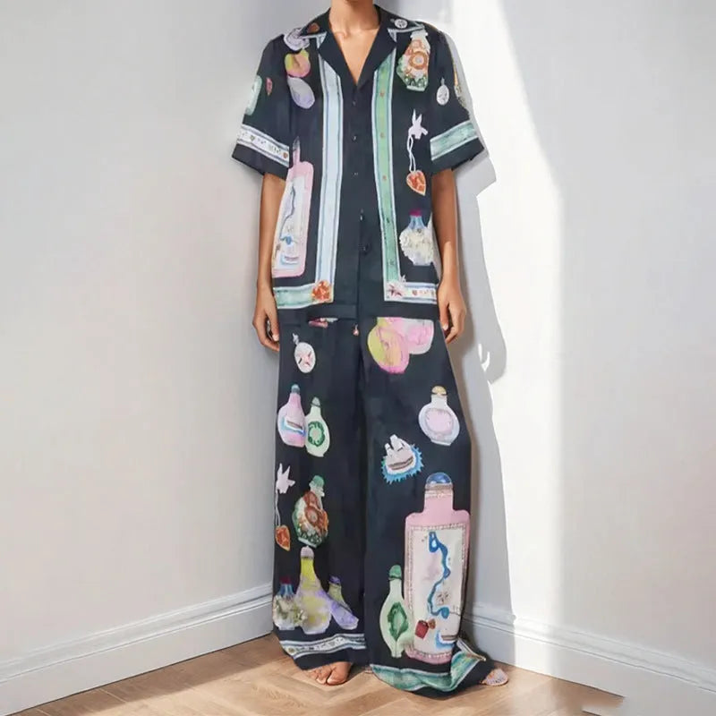 Black women's cardigan and pants set with cartoon animation pattern, shown laid flat.