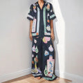 Black women's cardigan and pants set with cartoon animation pattern, shown laid flat.