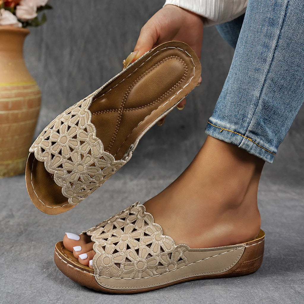 Black women's wedge beach sandals with a floral cutout pattern on the PVC upper.