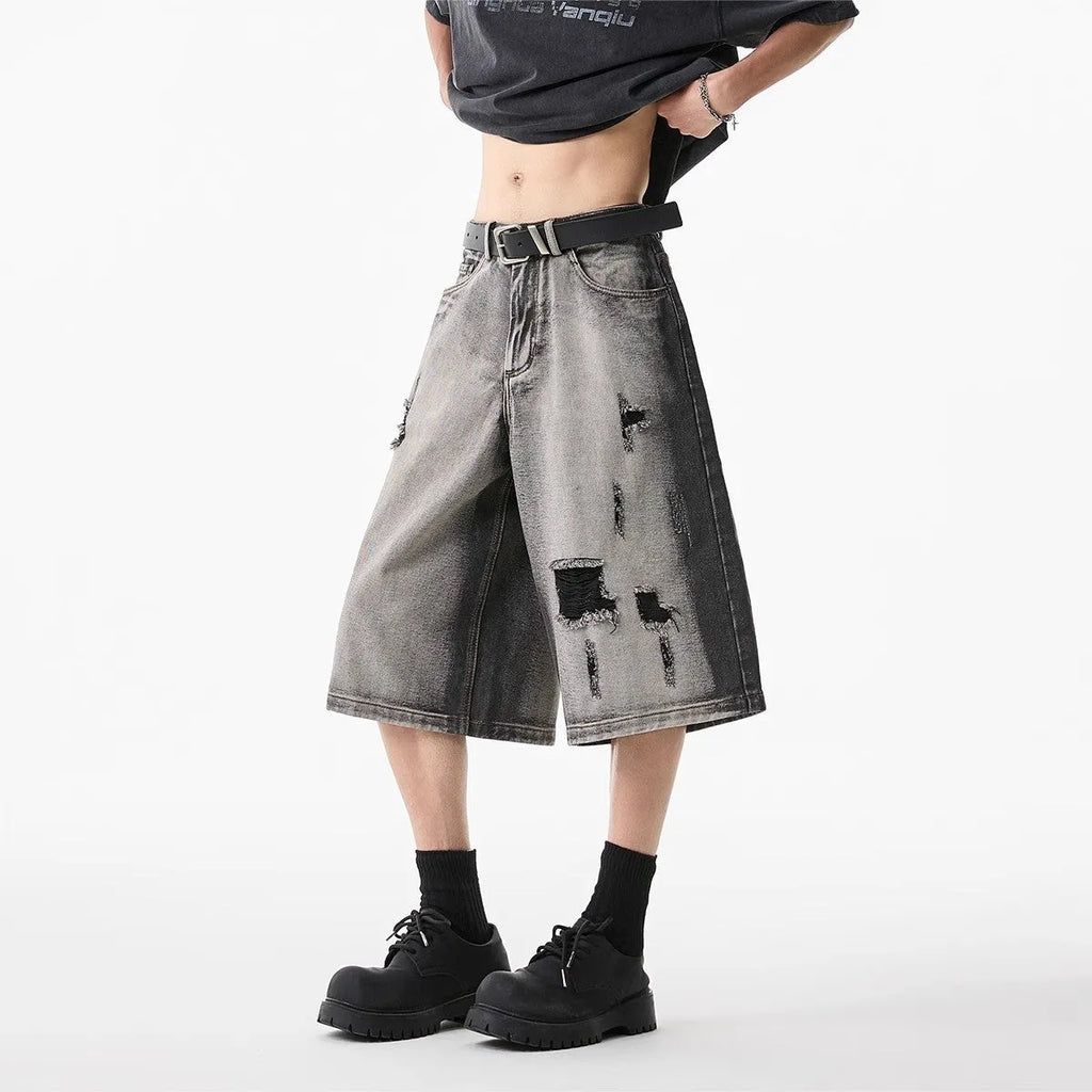 Grey women's denim shorts with a water washed finish, distressed holes, and a loose cropped fit.