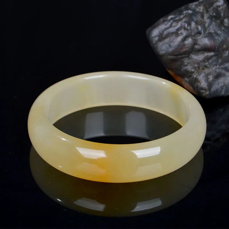 Natural light jade bracelet with a polished finish on a wrist, showing its Chinese style.