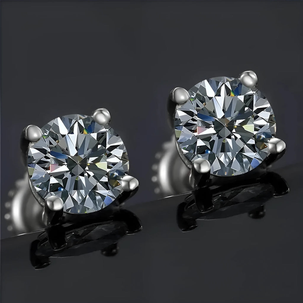 Geometric silver four claw moissanite stud earrings with screw back on black card.