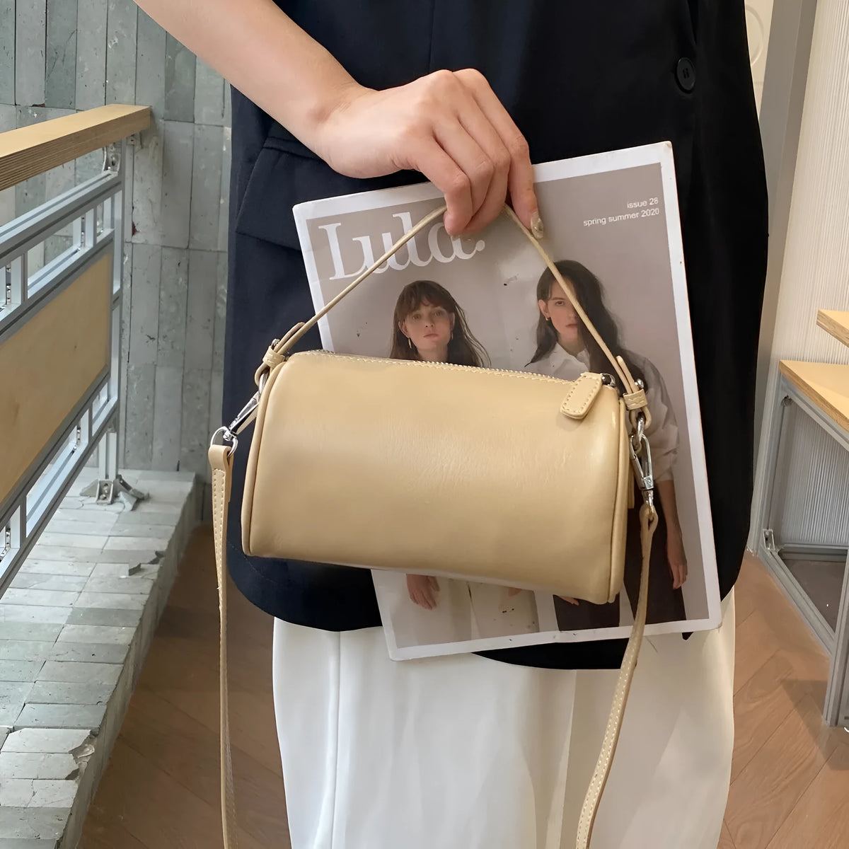 Soft genuine leather cylindrical crossbody bag for mobile phones in brown colour with visible stitching.