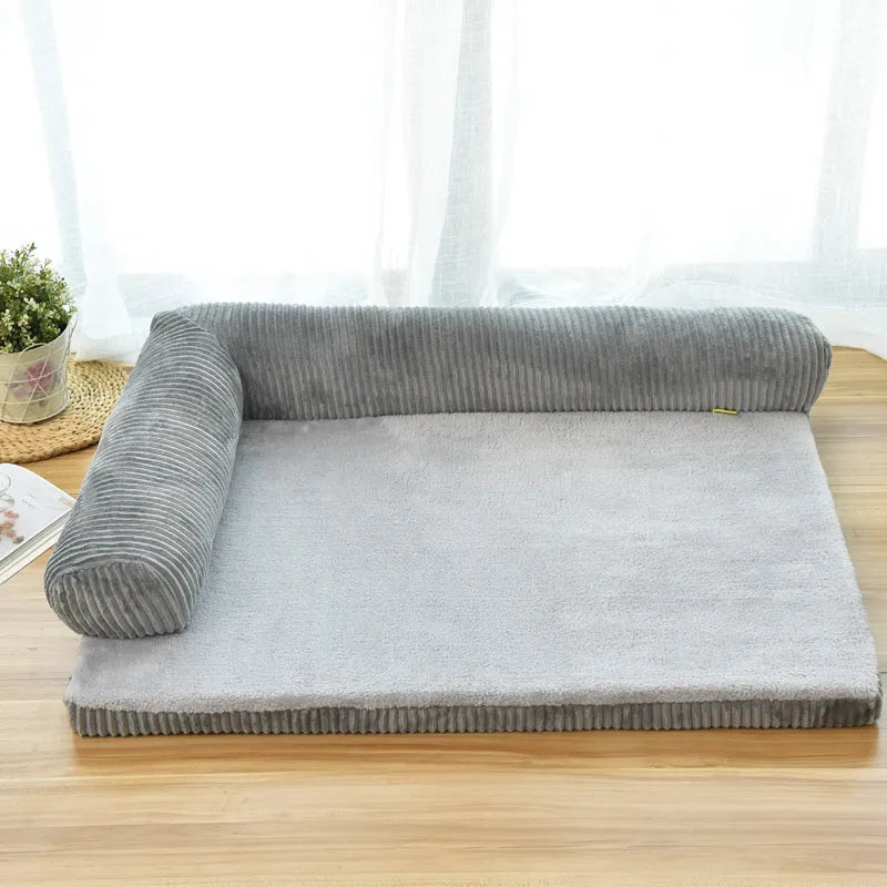 Corduroy pet sofa dog bed with bolster, shown in a grey colour on a wooden floor.