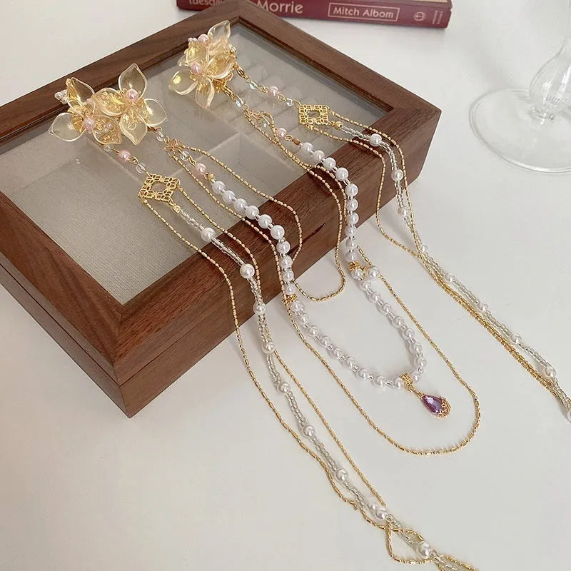 Gold coloured women's hairpin with a pearl, diamond flower and long decorative tassels.