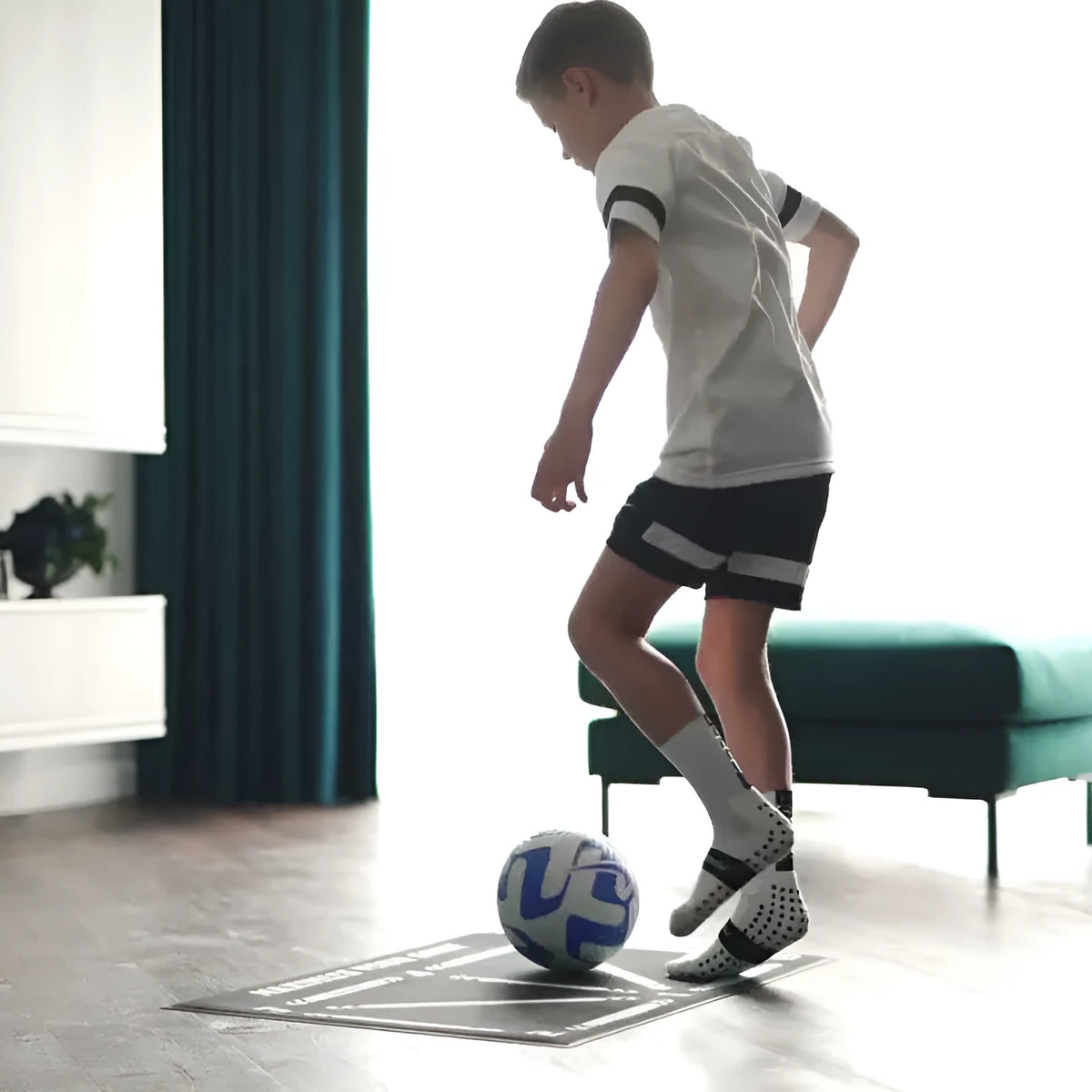 Large black rectangular rubber football training mat measuring 60x90 cm on a floor.