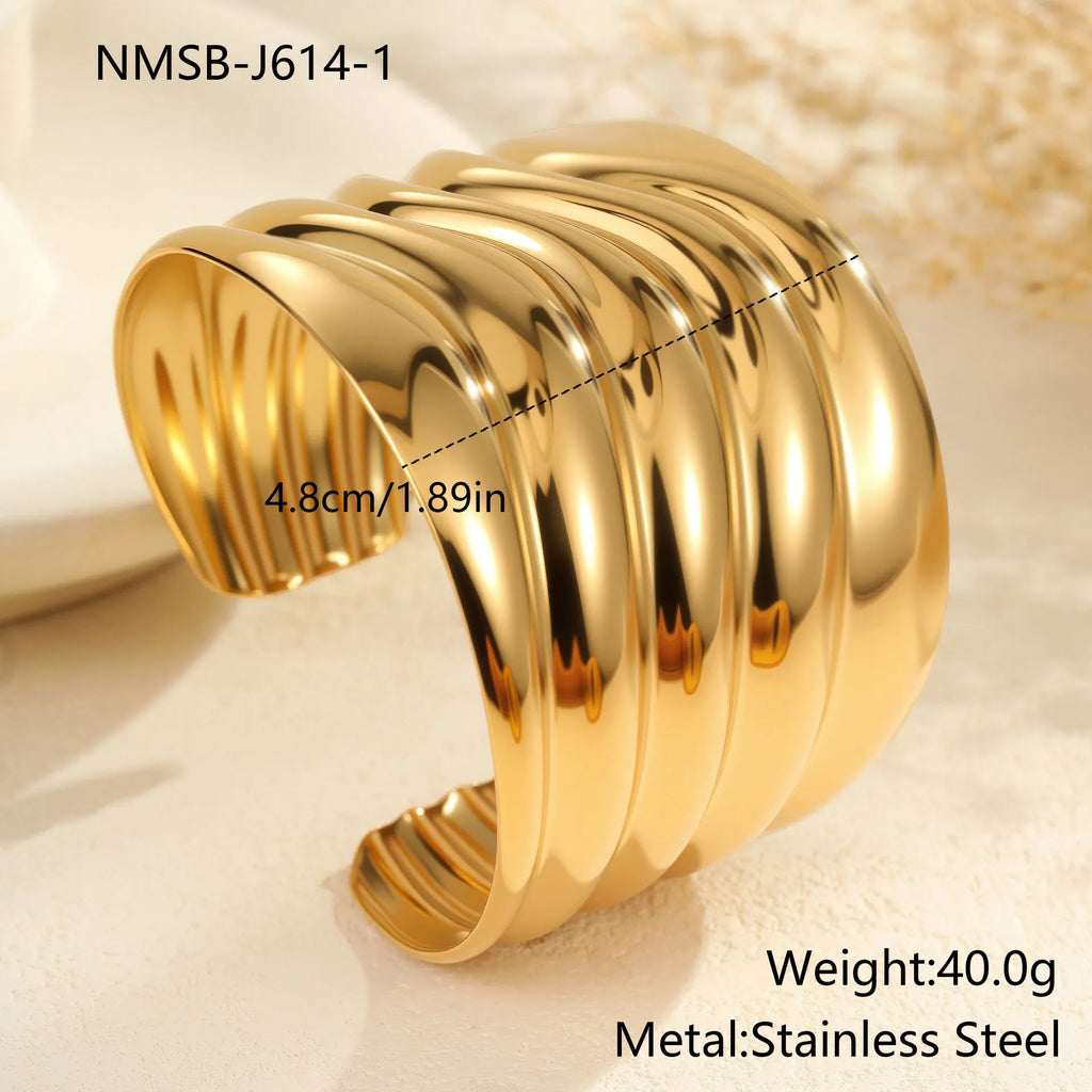 Gold-plated stainless steel bracelet with asymmetric geometric wave design and wide opening.