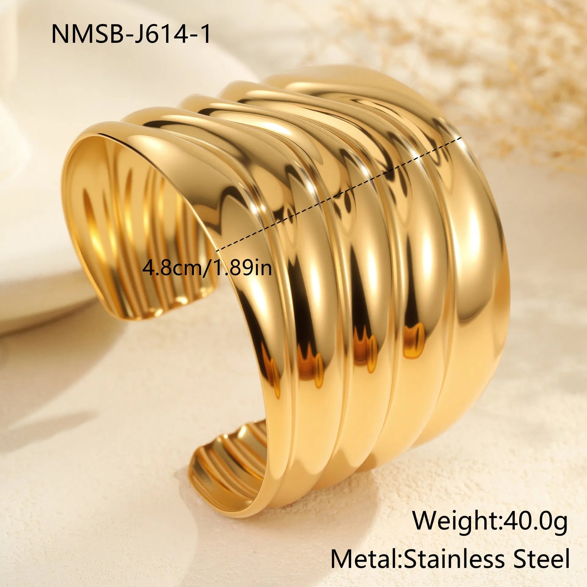Gold-plated stainless steel bracelet with asymmetric geometric wave design and wide opening.