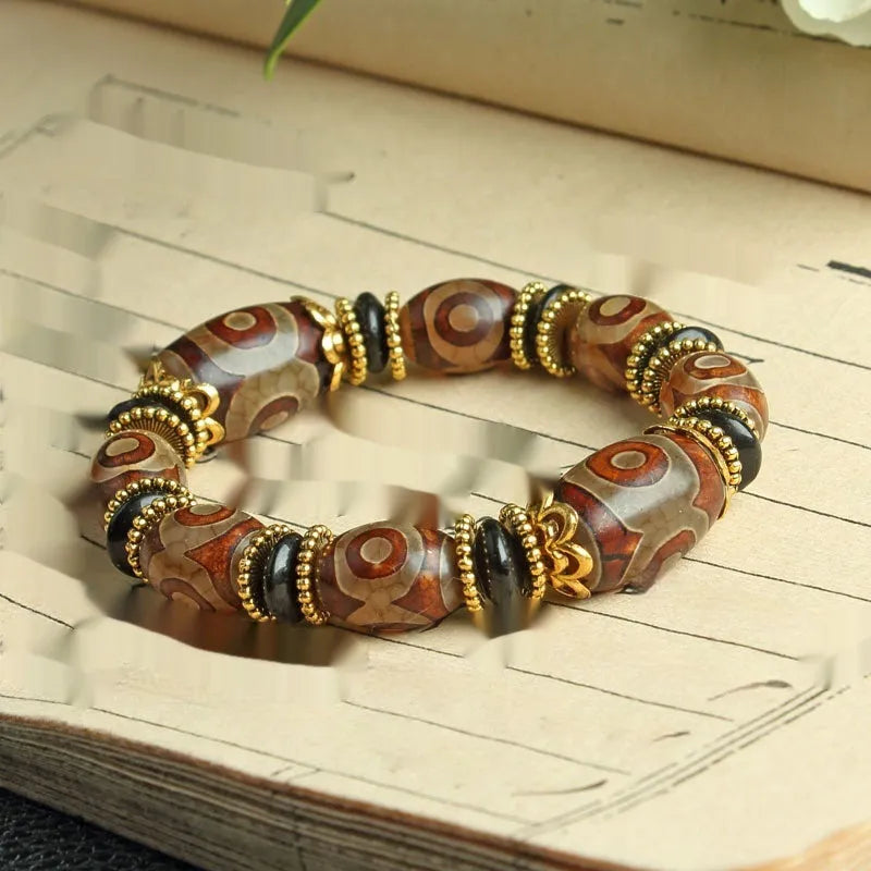 Distressed agate Tibetan bead bracelet with three-eye motifs and polished finish.