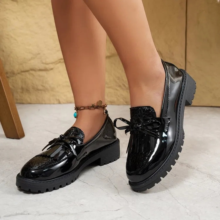 Women's brown artificial PU loafers with a black bow decoration on the vamp, shown on a white background.