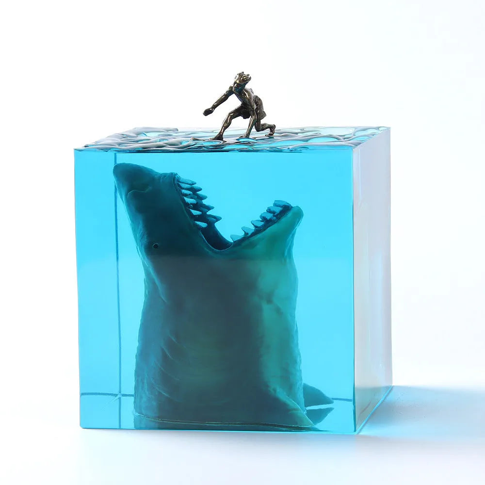 Clear epoxy resin ornament with shark surfing scene inside, on a plastic lamp holder base.