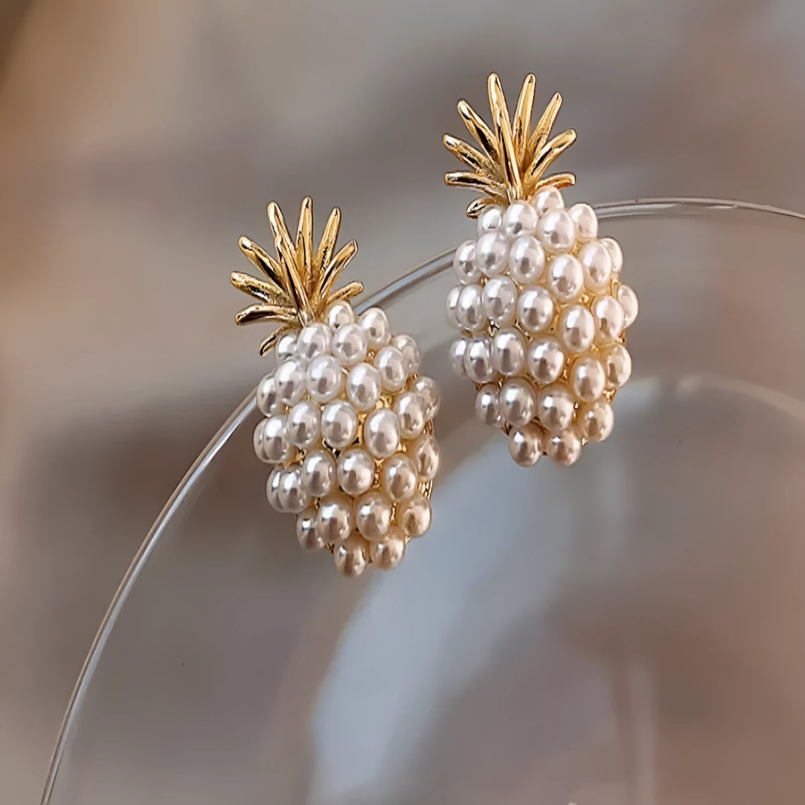 Gold colour Korean-style drop earrings featuring a pineapple and starfish design with pearl and gemstone inlay.