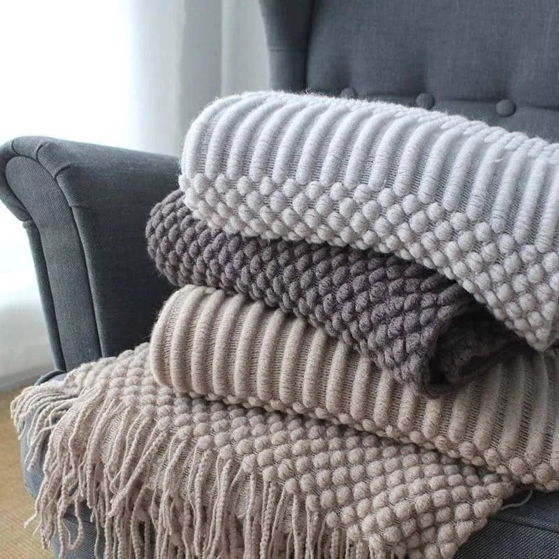 Small light grey polyester nap blanket folded on a sofa, showing its size.