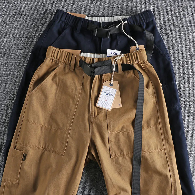 Man wearing khaki cotton work trousers with a flat front and mid-rise waist.