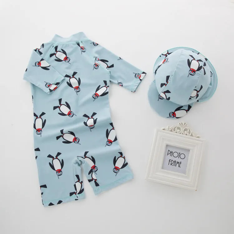 Boy's long sleeve penguin print swimsuit set with matching swimming cap on a white background.