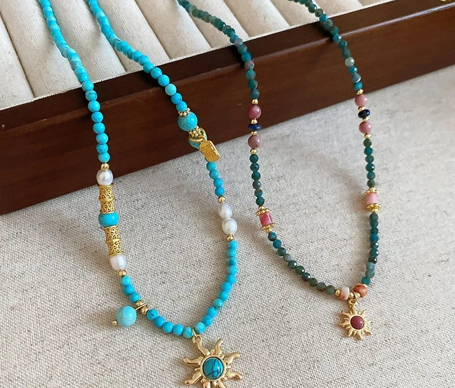 Freshwater pearl sun necklace with blue stone pendant on a gold-tone adjustable chain.