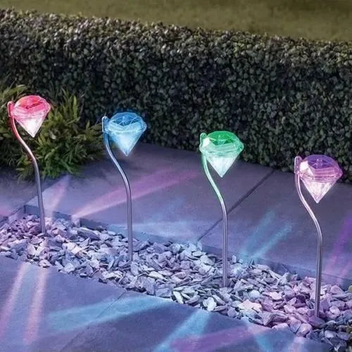 White solar-powered garden spotlight with adjustable head on a metal stake for outdoor use.