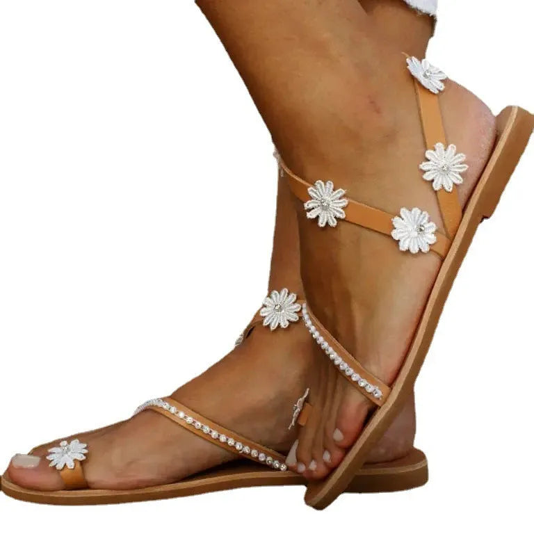 Brown women's Roman-style sandals with floral detail on the upper and a flat rubber sole.