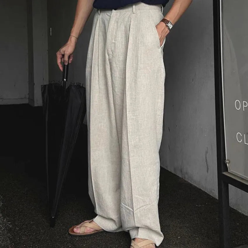 Man wearing loose fit apricot wide-leg cotton linen trousers with a zip fly and straight leg opening.