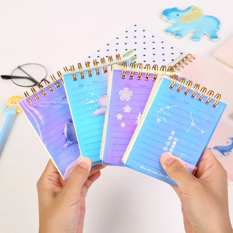 Four A7 spiral-bound pocket notebooks showing different PP cover designs: Constellation, Sakura, Universe, and Ocean.