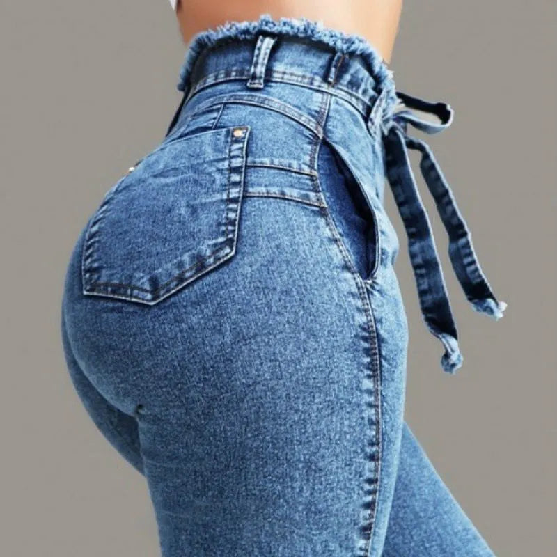 A pair of distressed grey fringed jeans made from Cowboy denim fabric on a neutral background.