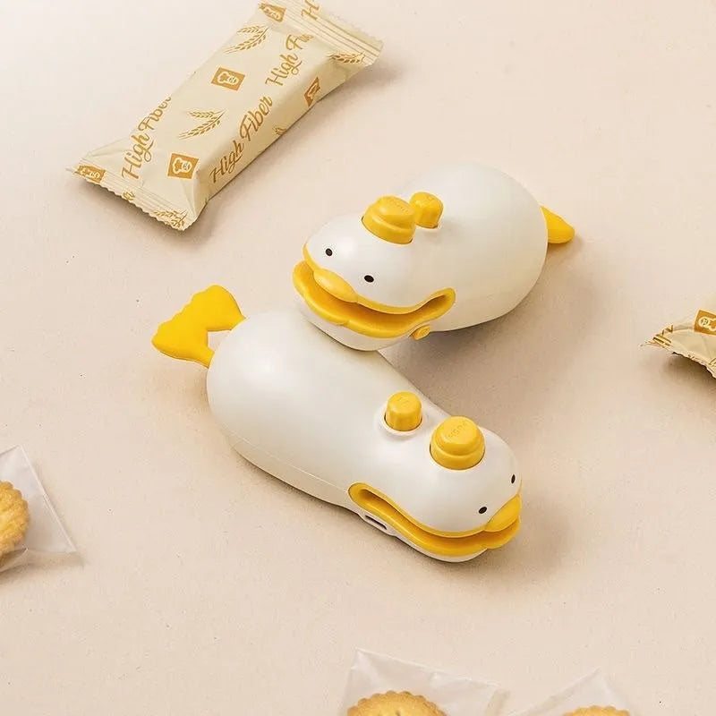 Small yellow duck-shaped rechargeable handheld sealing machine with USB charging cable.