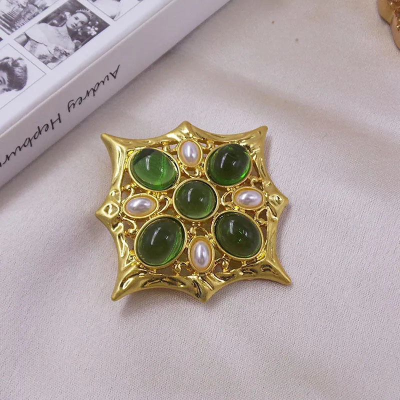 Close-up of a metallic medieval baroque cross brooch with crystal details on a dark background