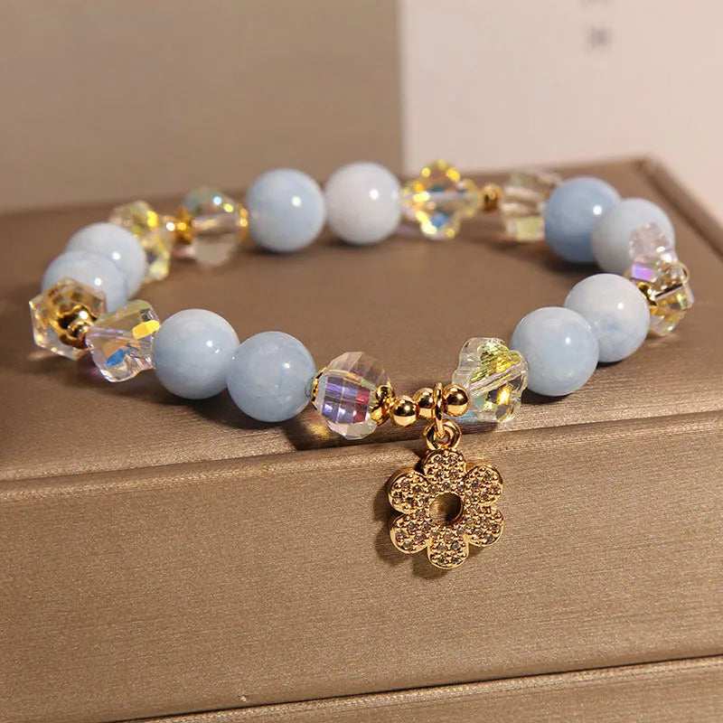 Women's aquamarine crystal bracelet with four-leaf clover charm and pearl accents on wrist