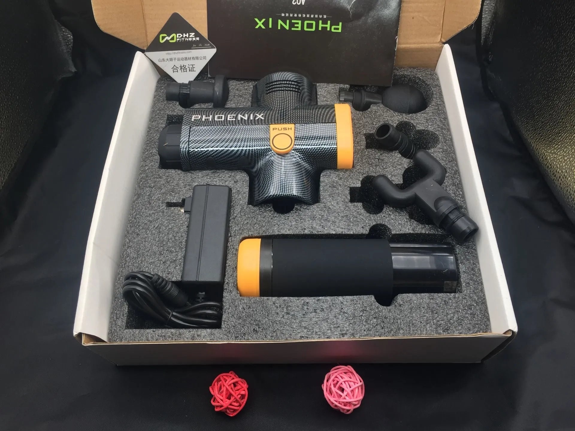 Black fascia massage gun with four removable heads on a grey background