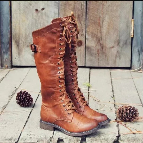 A pair of black chunky heel high leg boots with a round toe on a solid background.
