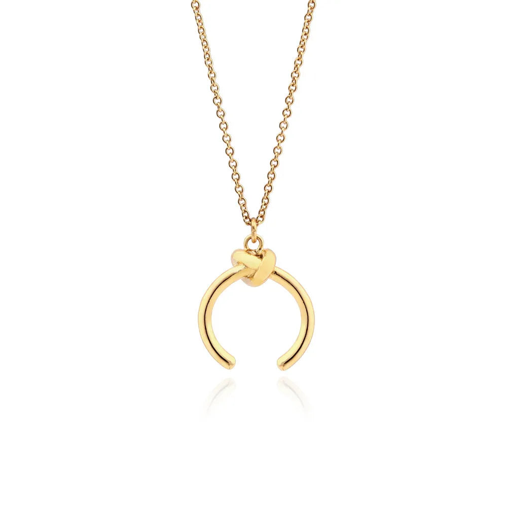 Close-up of a geometric copper pendant necklace with a gold electroplated finish on an adjustable cross chain.