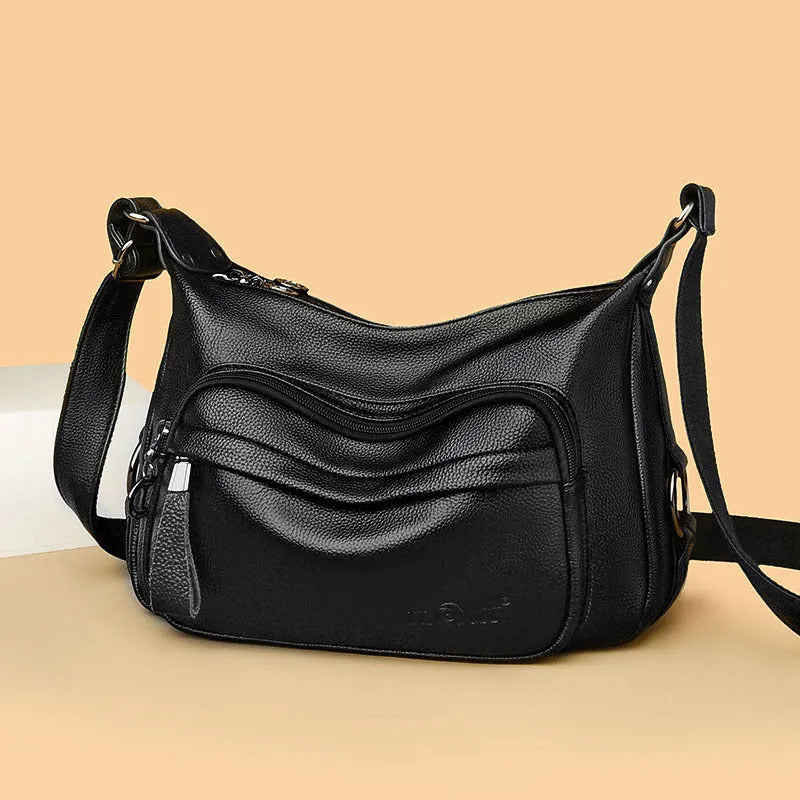 Large blue women's crossbody shoulder bag with a zipper and soft handle, shown with internal organiser pockets.