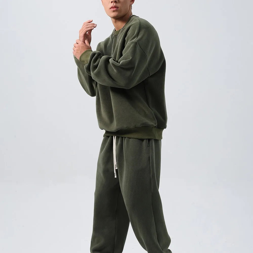 Men's loose-fit polar fleece sports suit in black, showing the long sleeve crew neck coat and matching padded trousers.