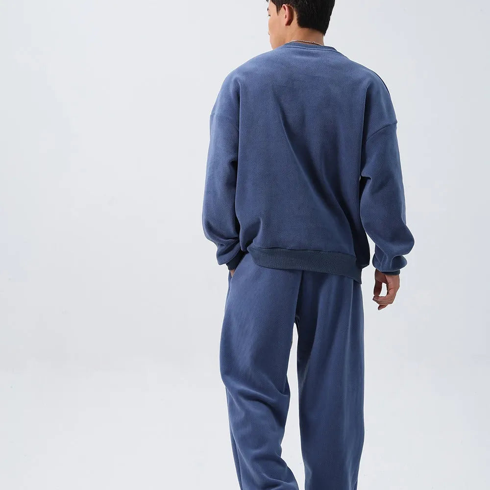 Men's loose-fit polar fleece sports suit in black, showing the long sleeve crew neck coat and matching padded trousers.