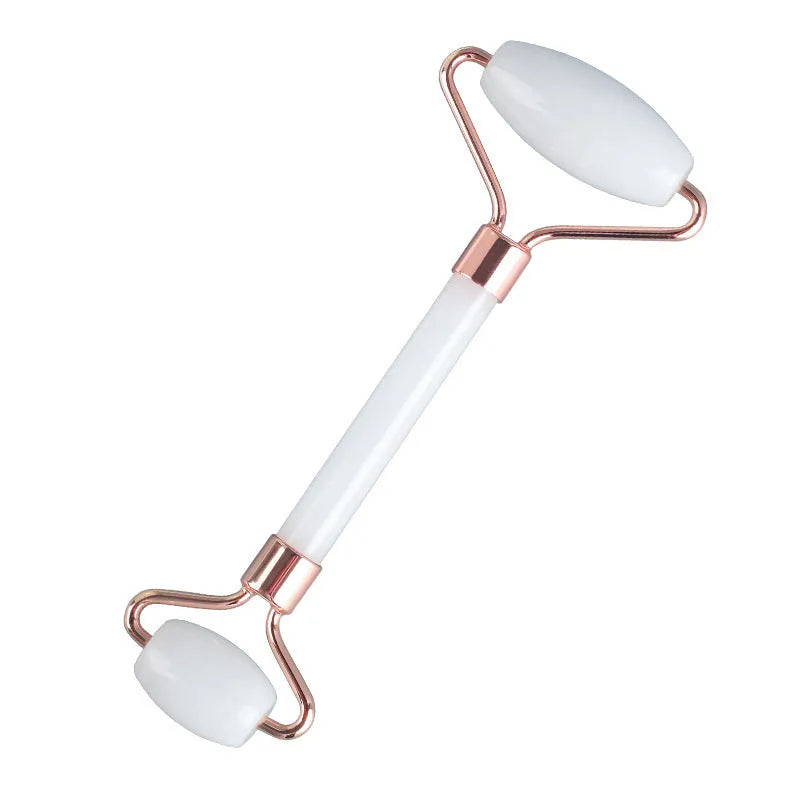 White jade facial roller and gua sha board set on a plain surface.
