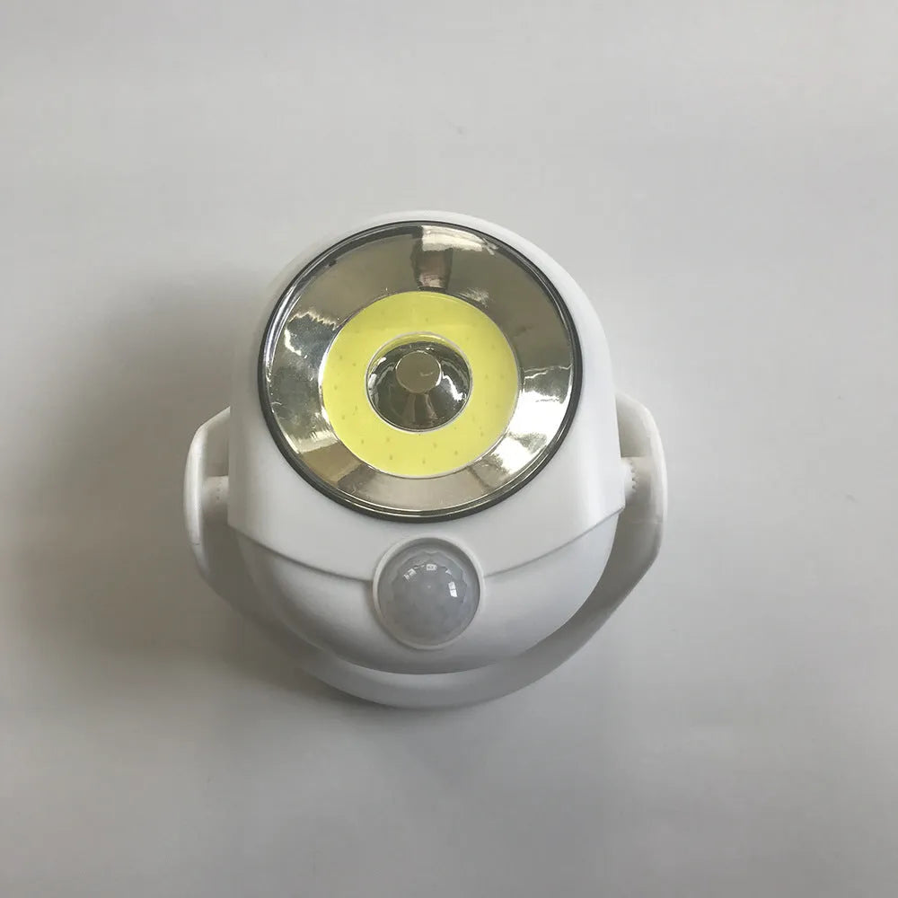 White Atomic Angel induction light unit on a surface, showing its compact 13.3cm by 9.8cm by 15.8cm dimensions.