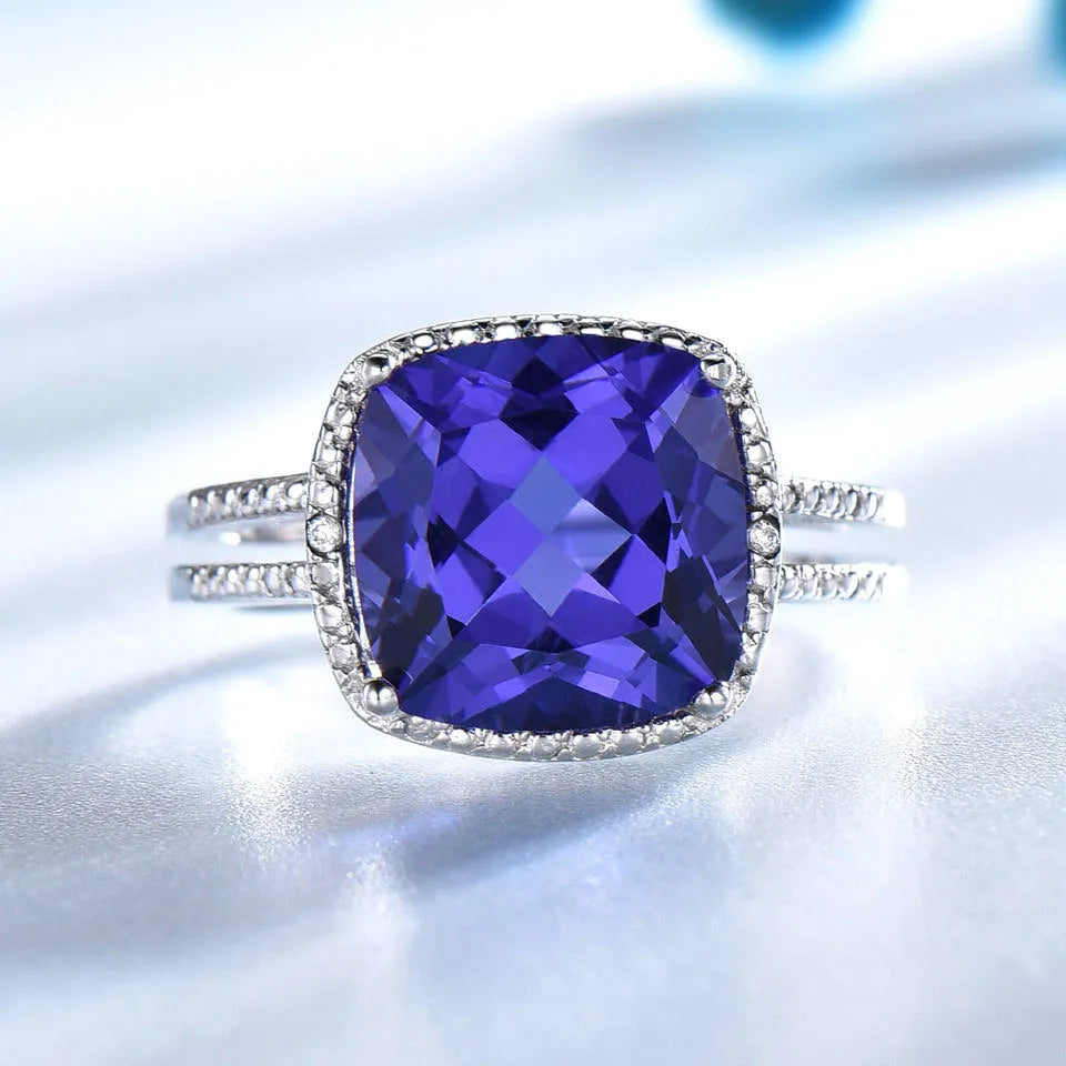 Blue tanzanite gemstone set in a sterling silver women's ring on a plain background.