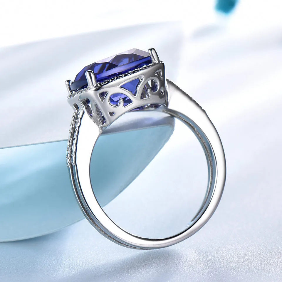 Blue tanzanite gemstone set in a sterling silver women's ring on a plain background.