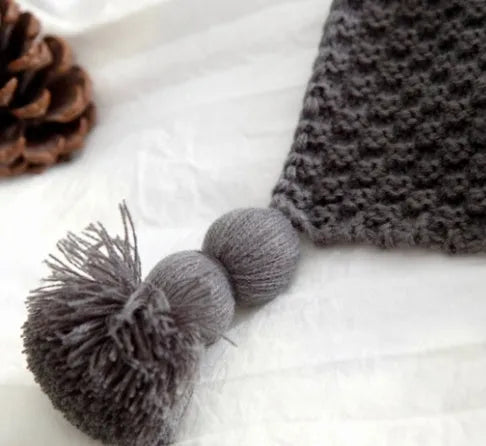 Nordic style fringed knit throw blanket in a neutral colour, shown draped over a sofa.