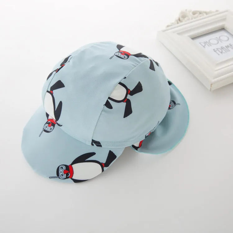 Boy's long sleeve penguin print swimsuit set with matching swimming cap on a white background.